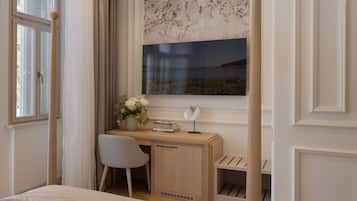 A bedroom with a bed, a desk, a chair, a window with a view of the sea, and a curtain.