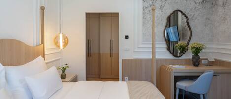Quarto de hotel com cama, escrivaninha, cadeira, espelho e parede com padrão floral.