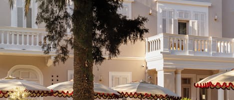 Hotel con balcón, sombrillas de exterior y una palmera.