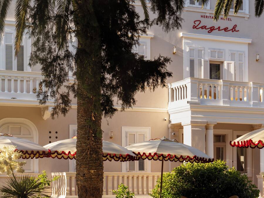 Un hôtel doté d’un balcon, de parasols et d’un palmier.