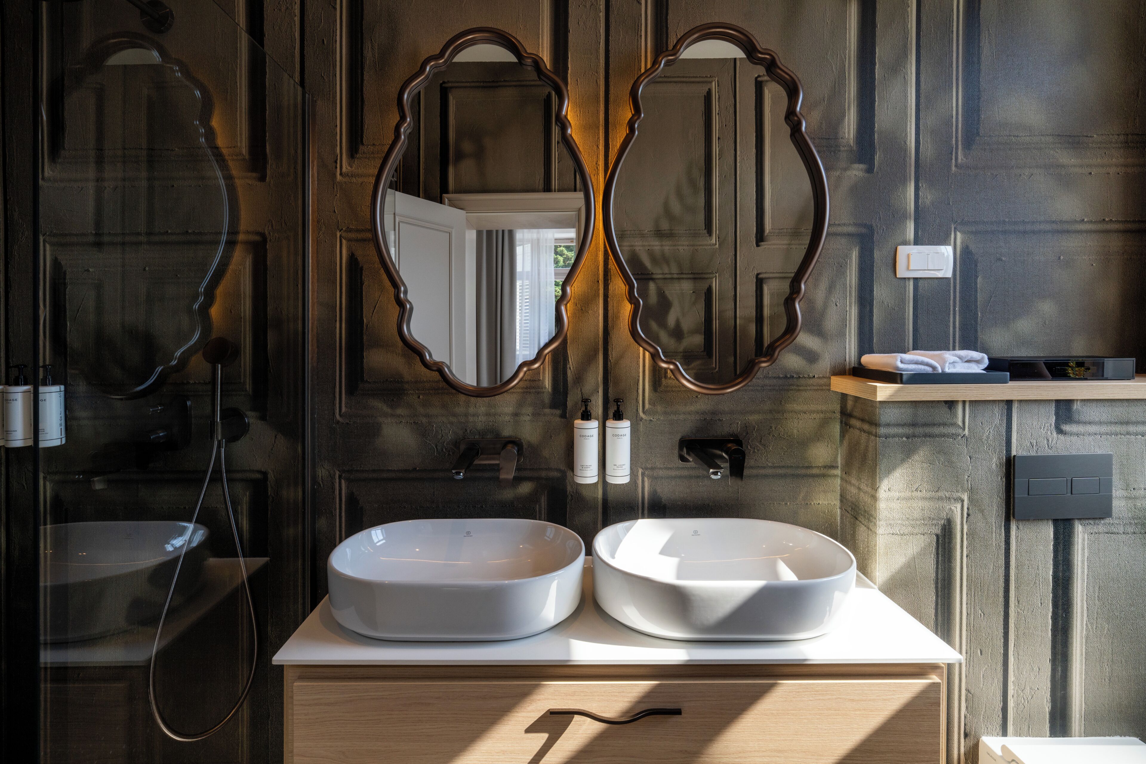 A bathroom with two sinks, a mirror, and a shower.