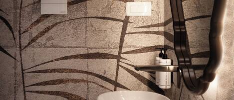 Un baño de diseño moderno, con un espejo grande, un lavamanos blanco y una pared con diseño de hojas.
