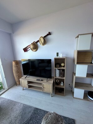 Una sala moderna con televisor de pantalla plana, mueble de madera para entretenimiento y un perchero fijado a la pared.