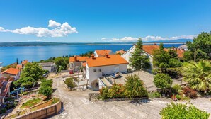 Ein Küstendorf mit terrakottafarbenen Dächern, einem gepflasterten Platz und Blick auf das Meer.