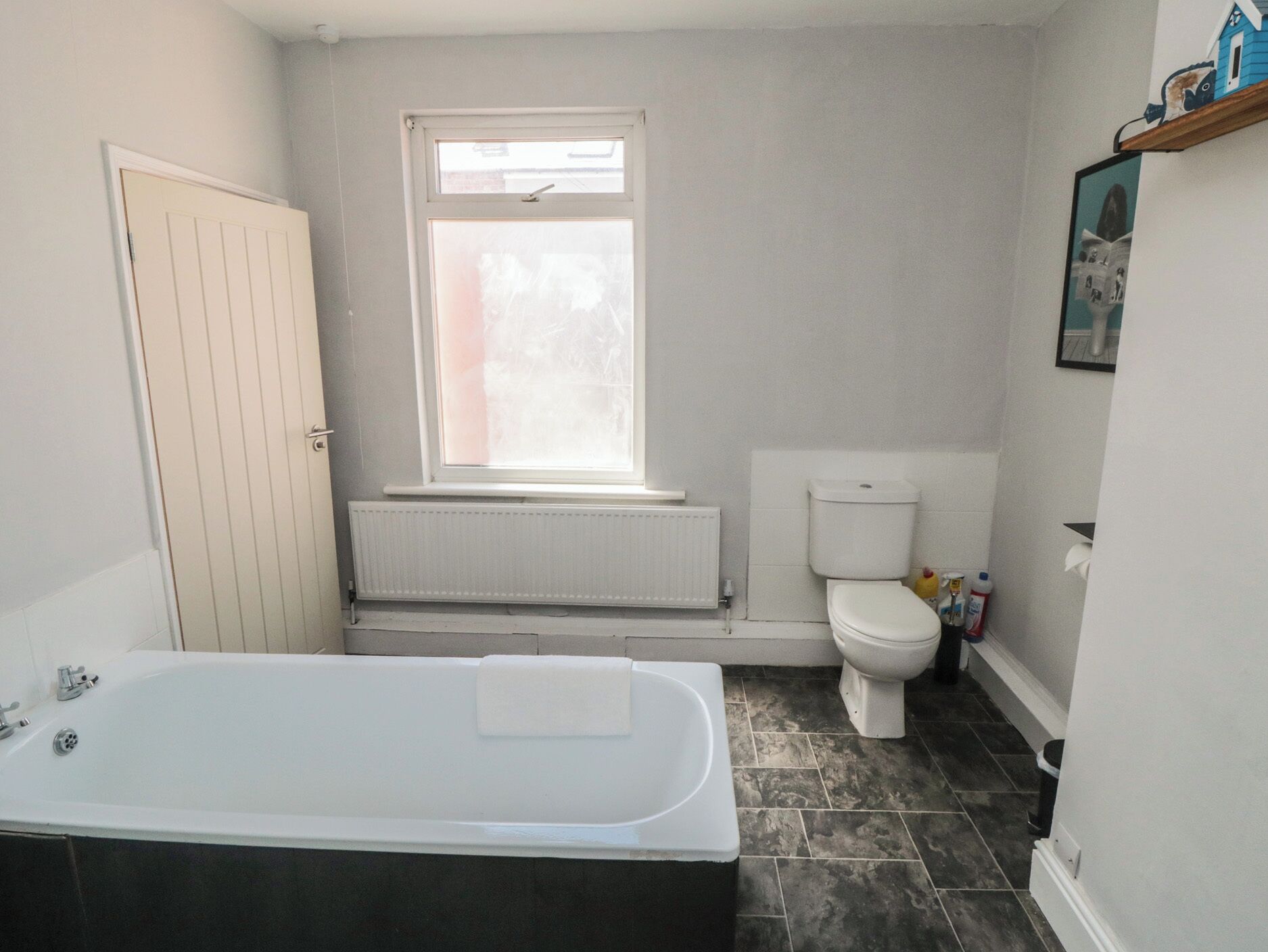 A bathroom with a bathtub, toilet, and window.