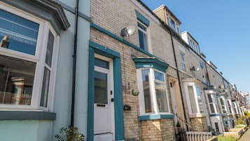 A row of terraced houses with bay windows, a brick facade, and a clear blue sky.