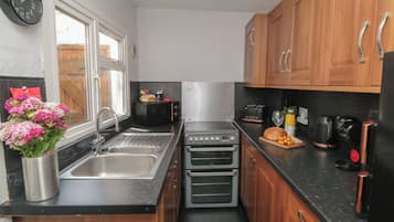 A compact kitchen with a sink, two ovens, a toaster, and a coffee maker.