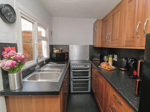 A compact kitchen with a sink, two ovens, a toaster, and a coffee maker. - Captain Jacks (Whitby)