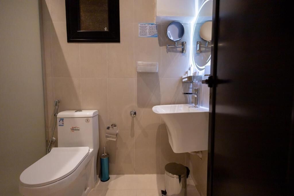 Een compacte badkamer met toilet, wastafel, spiegel en douche.
