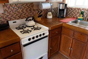 A kitchen with a gas stove, a kettle, a coffee maker, and a sink. - Casita de Oro | Playa Del Oro | Private Oasis | Pool (San Felipe)