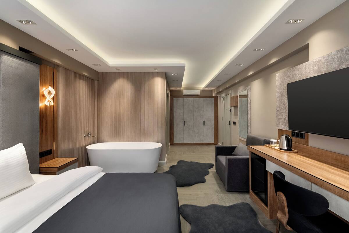 Ein modernes Hotelzimmer mit großem Bett, eigenem Badezimmer, Flachbildfernseher und Schreibtisch.