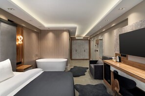 A modern hotel room with a large bed, a separate bathroom, a flat-screen TV, and a desk area. - Ramada by Wyndham Erzincan Ergan (Erzincan)