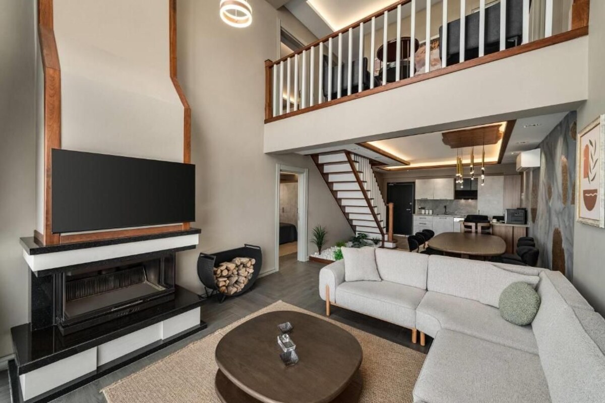 Una sala de estar moderna con una televisión de pantalla plana, una chimenea, un sofá y un comedor.