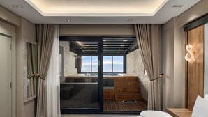 A modern hotel room with a large sliding glass door leading to a balcony, a wooden staircase, and a view of the mountains. - Ramada by Wyndham Erzincan Ergan (Erzincan)