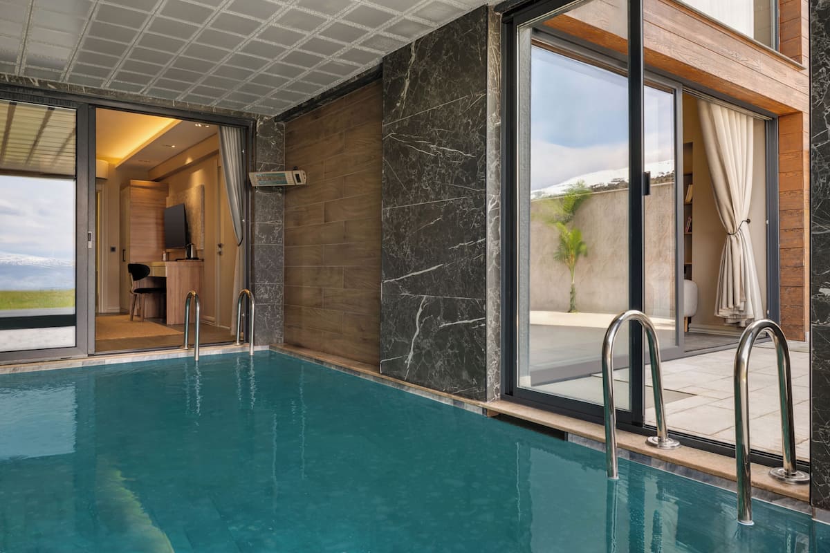 Ein Hallenbad mit Blick auf eine Holzterrasse und eine Tür zu einem Raum.