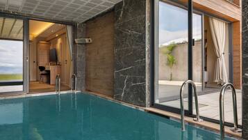 Una piscina interior con vista a una terraza de madera y una puerta que da a una habitación.