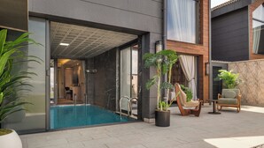 A modern building with a swimming pool, outdoor seating, and potted plants. - Ramada by Wyndham Erzincan Ergan (Erzincan)