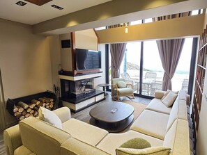 A modern living room with a fireplace, sofa, and a view of the outdoors. - Ramada by Wyndham Erzincan Ergan (Erzincan)
