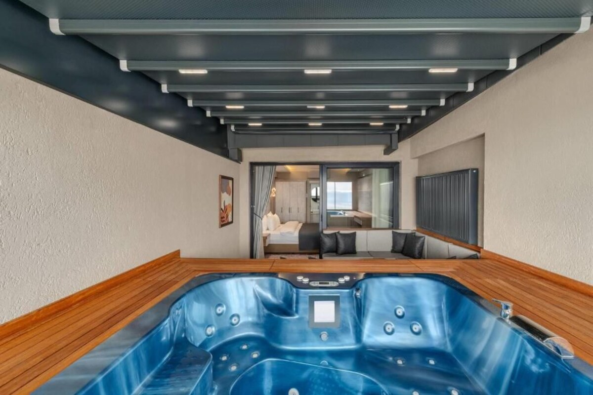 Un baño moderno con una bañera grande, piso de madera e iluminación empotrada en el techo.