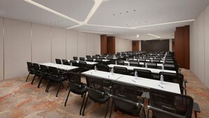 Una sala conferenze con file di tavoli e sedie, una moquette decorata e un moderno design del soffitto.