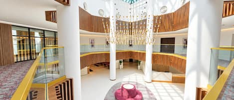 A multi-level atrium with a glass ceiling, wooden paneling, and a central seating area.