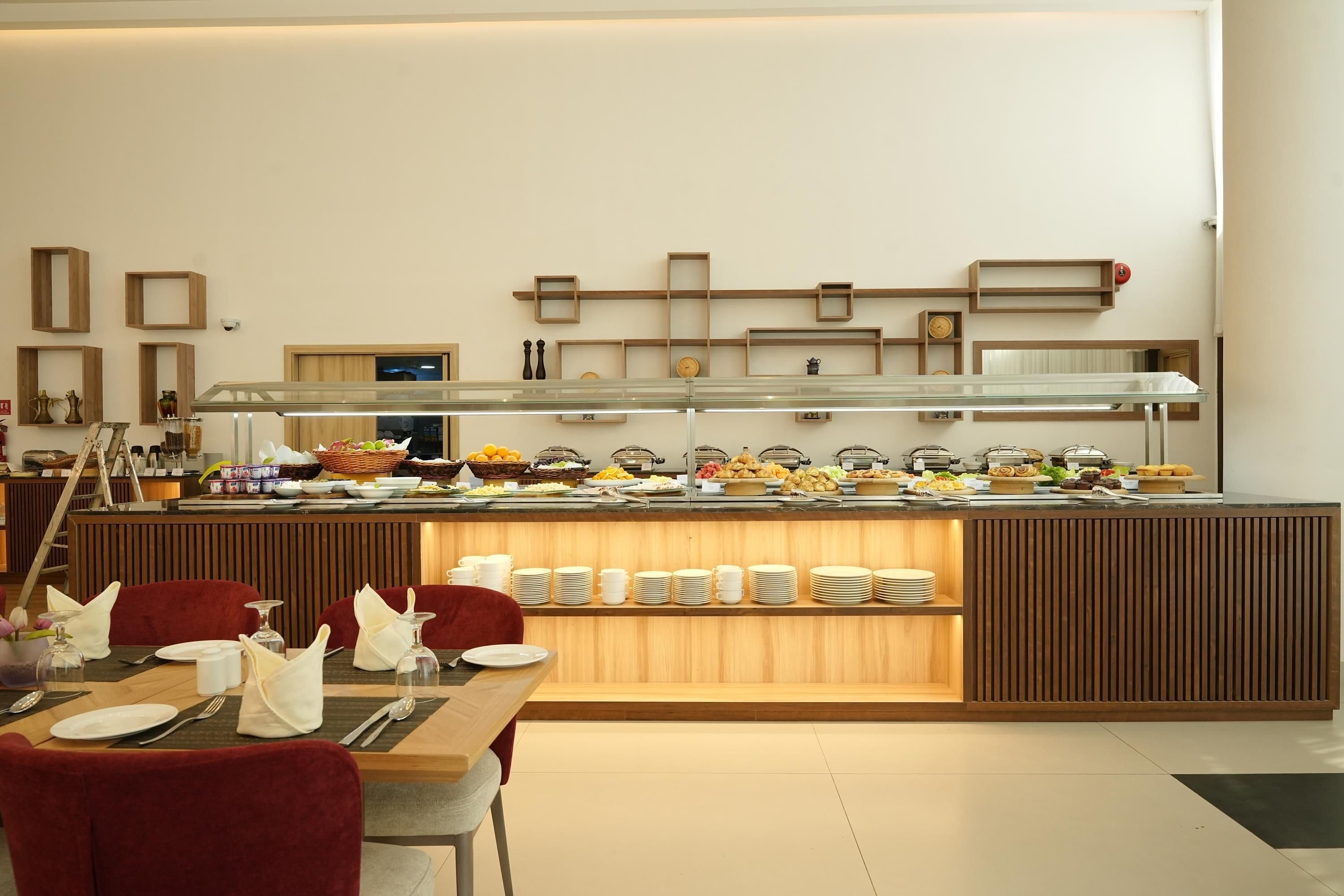 A buffet setup with various food items and a seating area with tables and chairs.