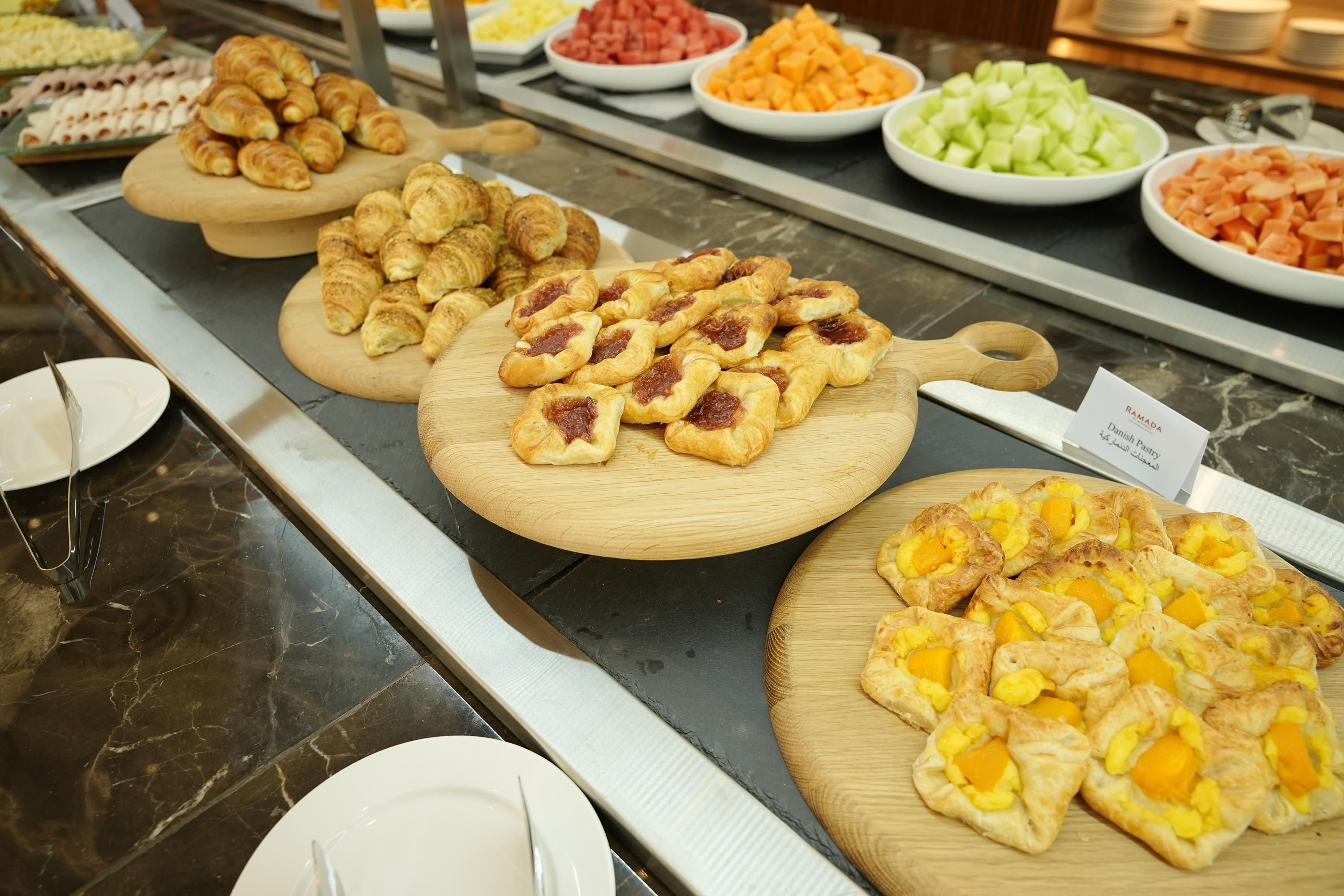 A buffet with various food items including pastries and fruits.
