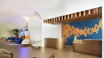 A modern reception area with a blue wall and wooden panel design, a seating area with sofas and chairs, and a coffee table.