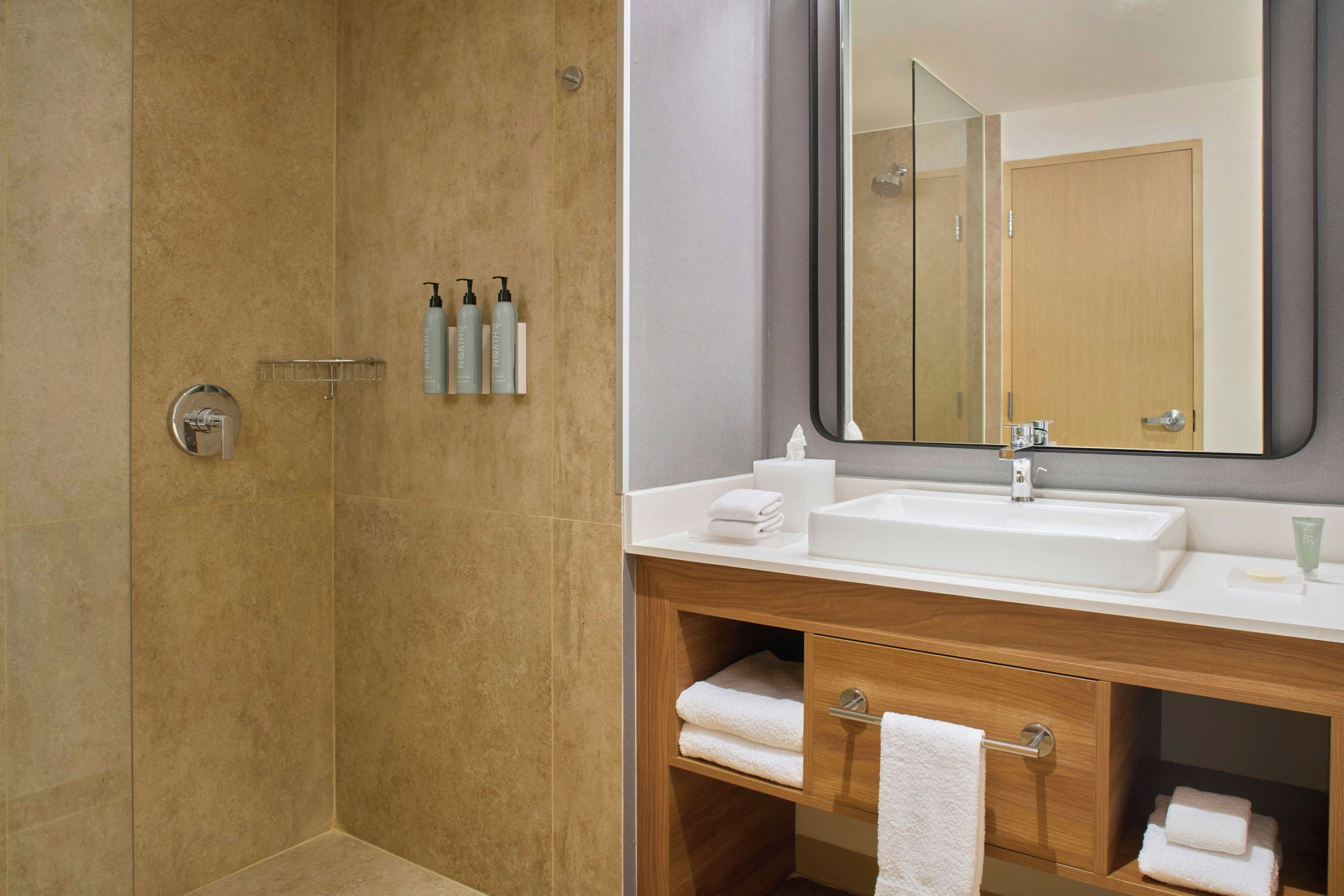 A modern bathroom with a shower, a sink, and a vanity.