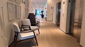 A hotel corridor with modern chairs, wooden flooring, and an elevator. - Residence Inn by Marriott Guadalajara Country Club (Guadalajara)