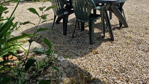 Kivitalo, jossa on sorapäällysteinen patio, pöytä ja tuolit sekä ikkuna, jossa on sälekaihtimet.