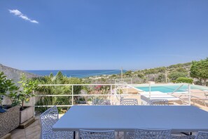 Eine Terrasse mit Pool, Sitzgelegenheiten im Freien und Meerblick.