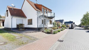 A residential building with a white facade, a red-tiled roof, a visible satellite dish, and a small garden area. - Apartment 'Für 2 Personen 43 M²' with Balcony and Wi-Fi (Mendig)