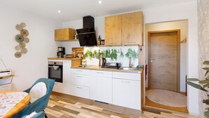 A compact kitchen with white cabinets, a black range hood, and a wooden countertop. - Apartment 'Für 2 Personen 43 M²' with Balcony and Wi-Fi (Mendig)