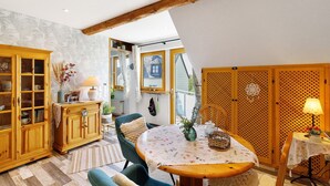 A cozy room with a wooden dining table, a green chair, a cabinet with glass doors, and a patterned wall. - Apartment 'Für 2 Personen 43 M²' with Balcony and Wi-Fi (Mendig)
