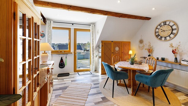 A dining area with a table, chairs, and a clock on the wall. - Apartment 'Für 2 Personen 43 M²' with Balcony and Wi-Fi (Mendig)