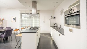 Una cocina moderna con una isla central, armarios blancos y una campana extractora de acero inoxidable.