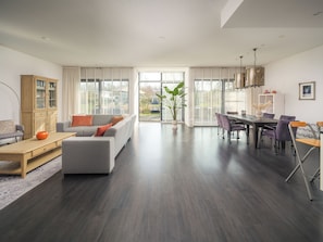 A modern living room with a sofa, coffee table, and dining area with chairs and a table.