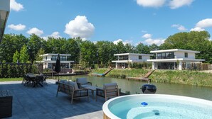 A modern house with a pool, outdoor furniture, and a hot tub. - Luxury 10-person villa on the water with hot tub, private jetty, spacious terrace and 4 bedrooms. Located at Villa Resort Harderwold, near Harderwijk and the Veluwemeer! (Zeewolde)