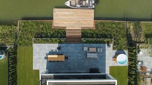 A modern outdoor deck with a pool, seating area, and a boat dock. - Luxury 10-person villa on the water with hot tub, private jetty, spacious terrace and 4 bedrooms. Located at Villa Resort Harderwold, near Harderwijk and the Veluwemeer! (Zeewolde)