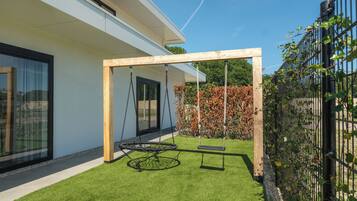 Een modern huis met een schommel en een omheinde tuin.