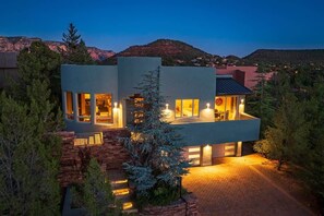 Ein modernes, zweistöckiges Haus mit großen Fenstern und einer Steintreppe.