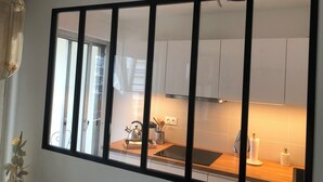 Eine Küche mit weißen Schränken, einer Holzarbeitsplatte und einem Fenster mit schwarzem Rahmen.