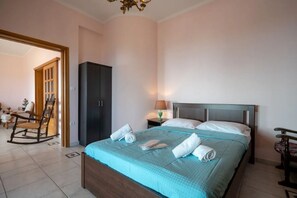 A hotel room with a bed, a wardrobe, a rocking chair, and a desk with a lamp. - Sea breeze maisonette sea view & pool (Koropi)