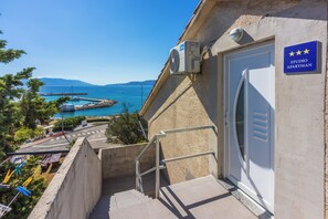 A building with a sign indicating it's a studio apartment, a staircase leading to the entrance, and a view of the sea. - Sunny studio for 2 with fantastic sea views (Novi Vinodolski)