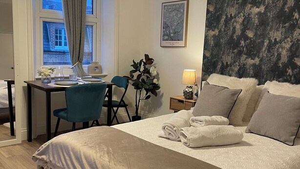 Ein Hotelzimmer mit einem Bett, einem Schreibtisch, einem Stuhl, einer Lampe und einem Bild an der Wand.