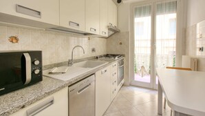 Een keuken met een magnetron, spoelbak, fornuis en vaatwasser.