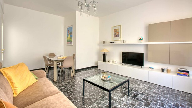 Een moderne woonkamer met een bank, salontafel, televisie en een eethoek.