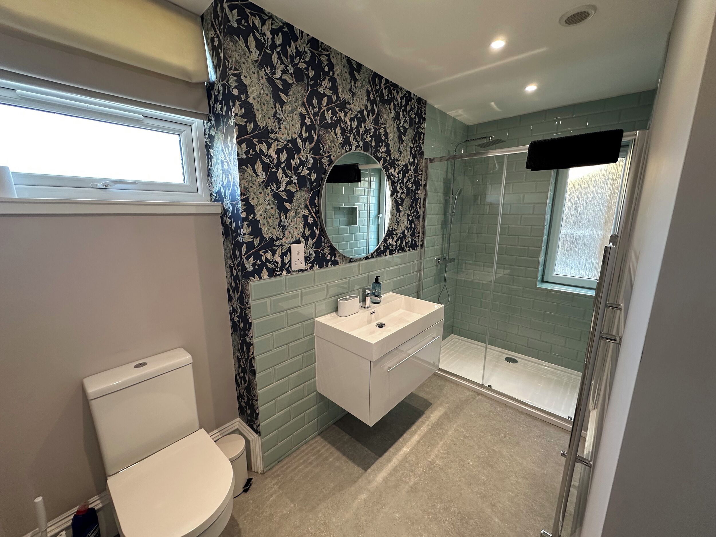 Et moderne badeværelse med toilet, vask med spejl og bruseniche.