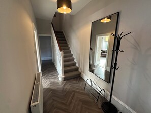 A staircase with a herringbone floor pattern, a large mirror, and a black floor lamp. - Abbotsford (Kelso)